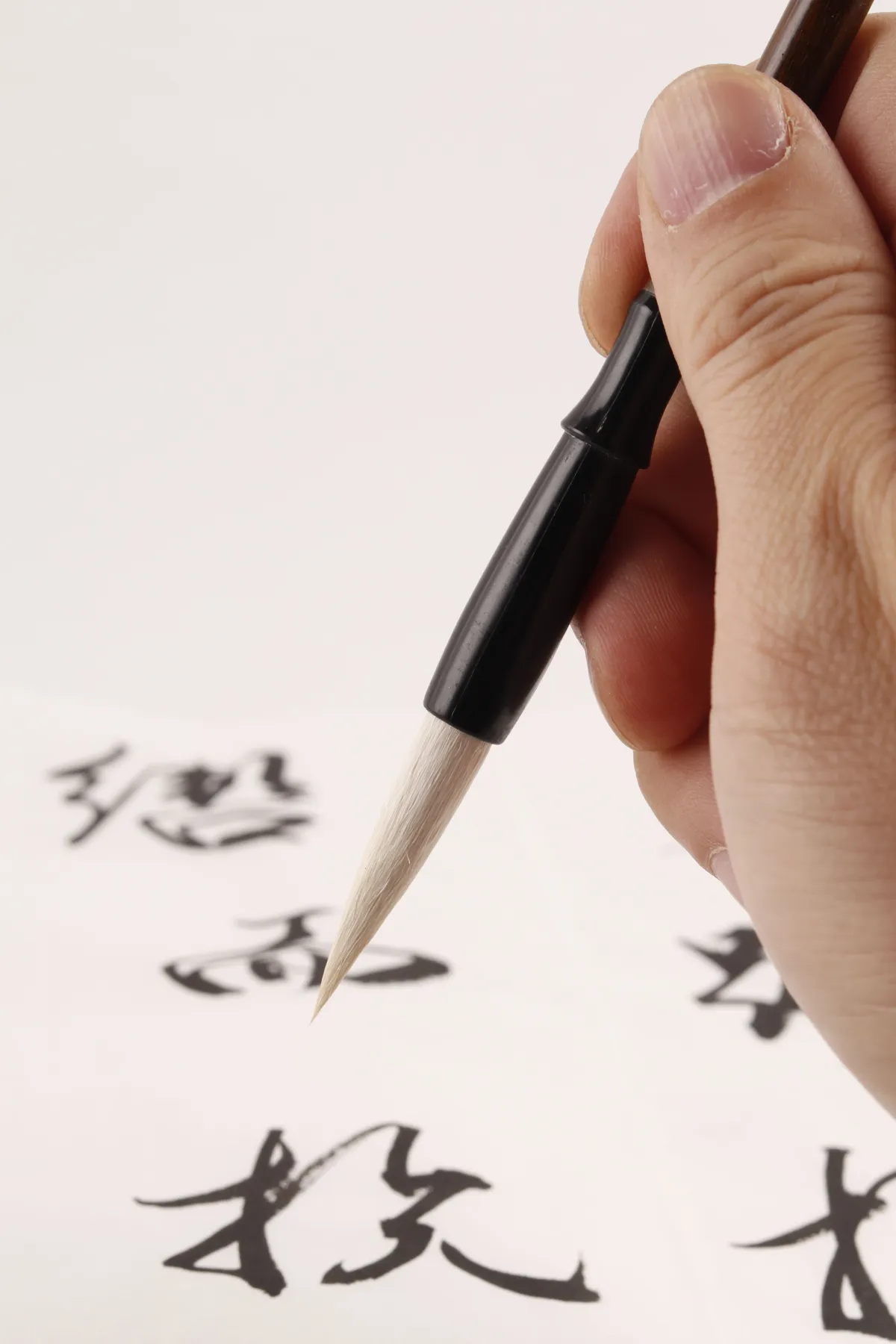 A calligrapher drawing a bold character in black ink with a brush on white washi paper
