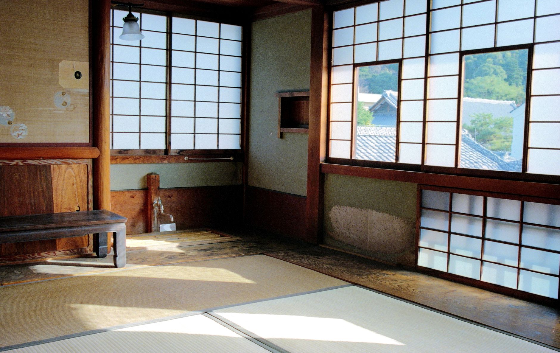 Traditional Japanese tokonoma alcove in a tea room displaying a hanging scroll and seasonal flower arrangement beside tatami mats.