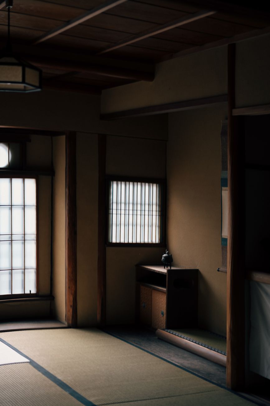 Traditional Japanese tokonoma alcove in a tea room displaying a hanging scroll and seasonal flower arrangement beside tatami mats.