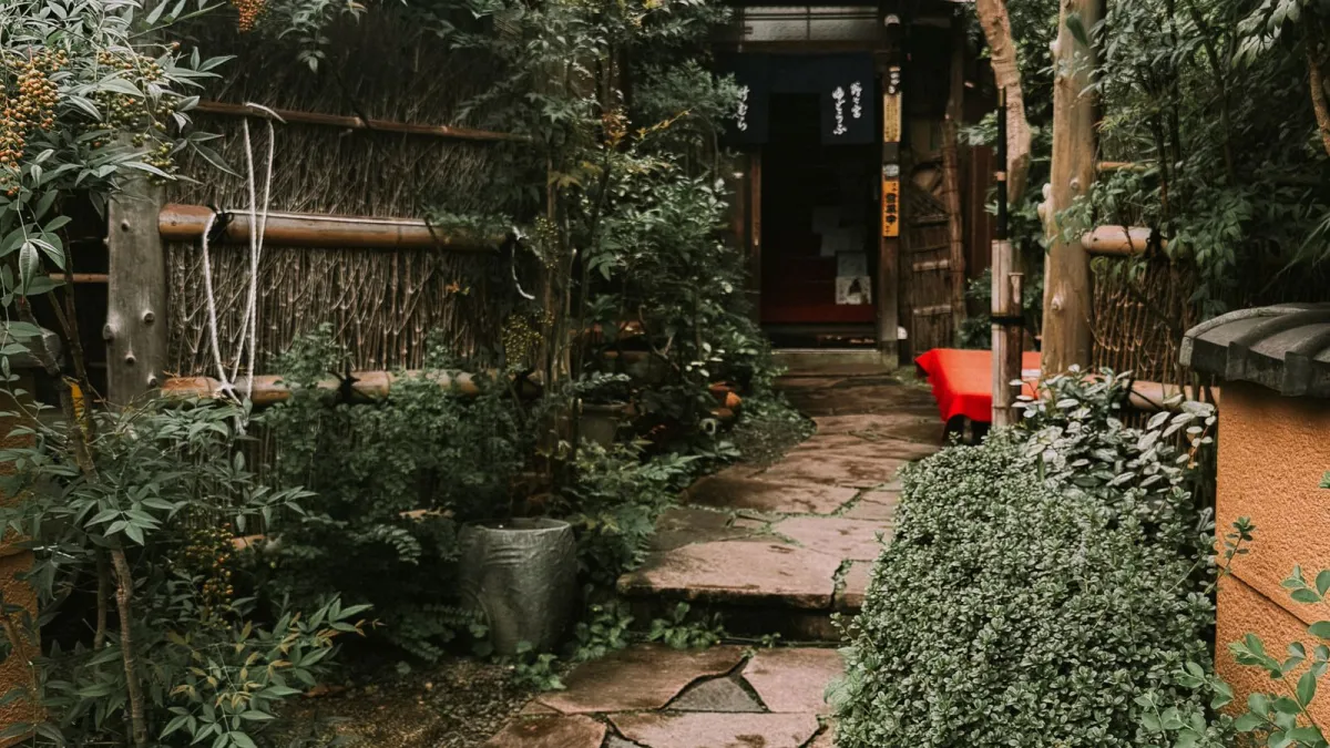 A row of wooden machiya teahouses with lattice fronts along a stone street in Gion, Kyoto