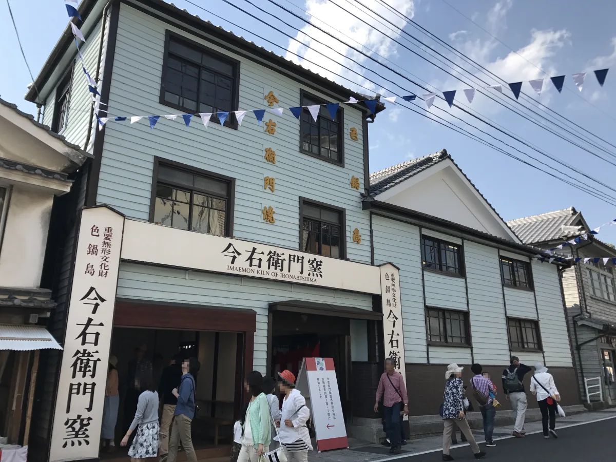 Historic Arita town street lined with traditional porcelain workshops and kilns nestled among forested hills in Saga Prefecture, Japan.