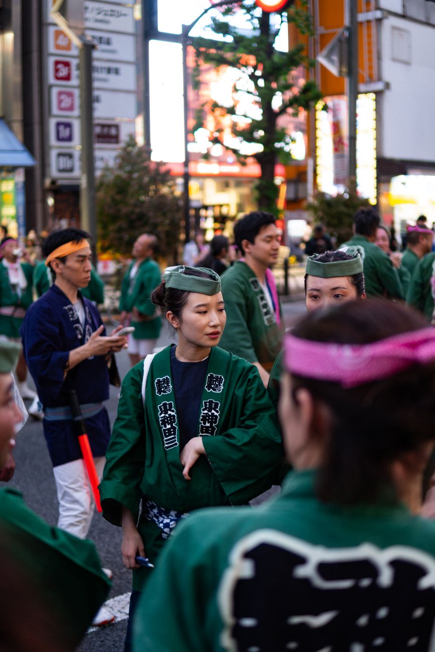 Bamboo tea whisk whisking bright green matcha in a black ceramic bowl during a spring cherry blossom festival ceremony.