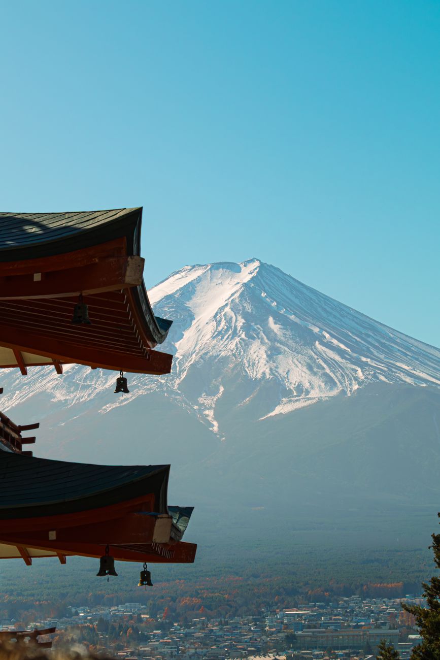 Mount Fuji rising above morning clouds with a traditional torii gate in the foreground at Lake Kawaguchi
