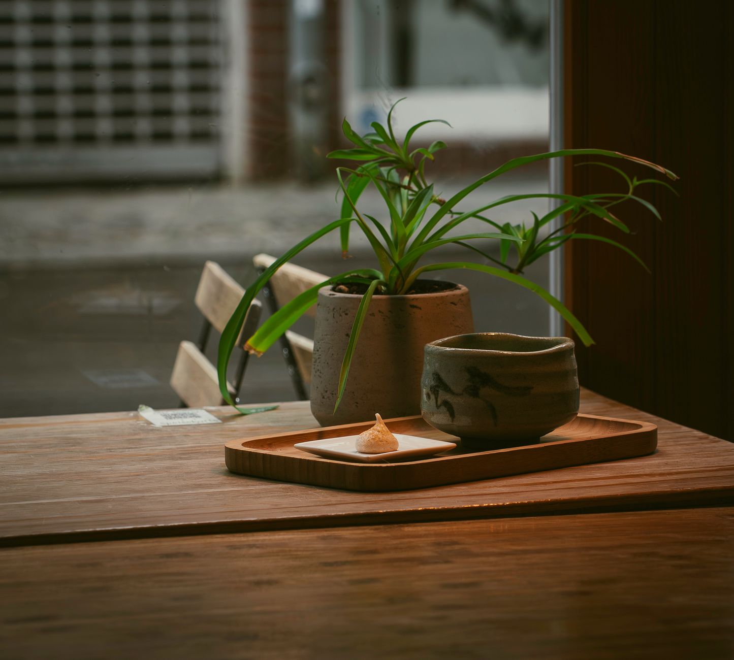 Traditional yunomi tea cup in earthy brown glaze resting on wooden table with green tea visible inside.