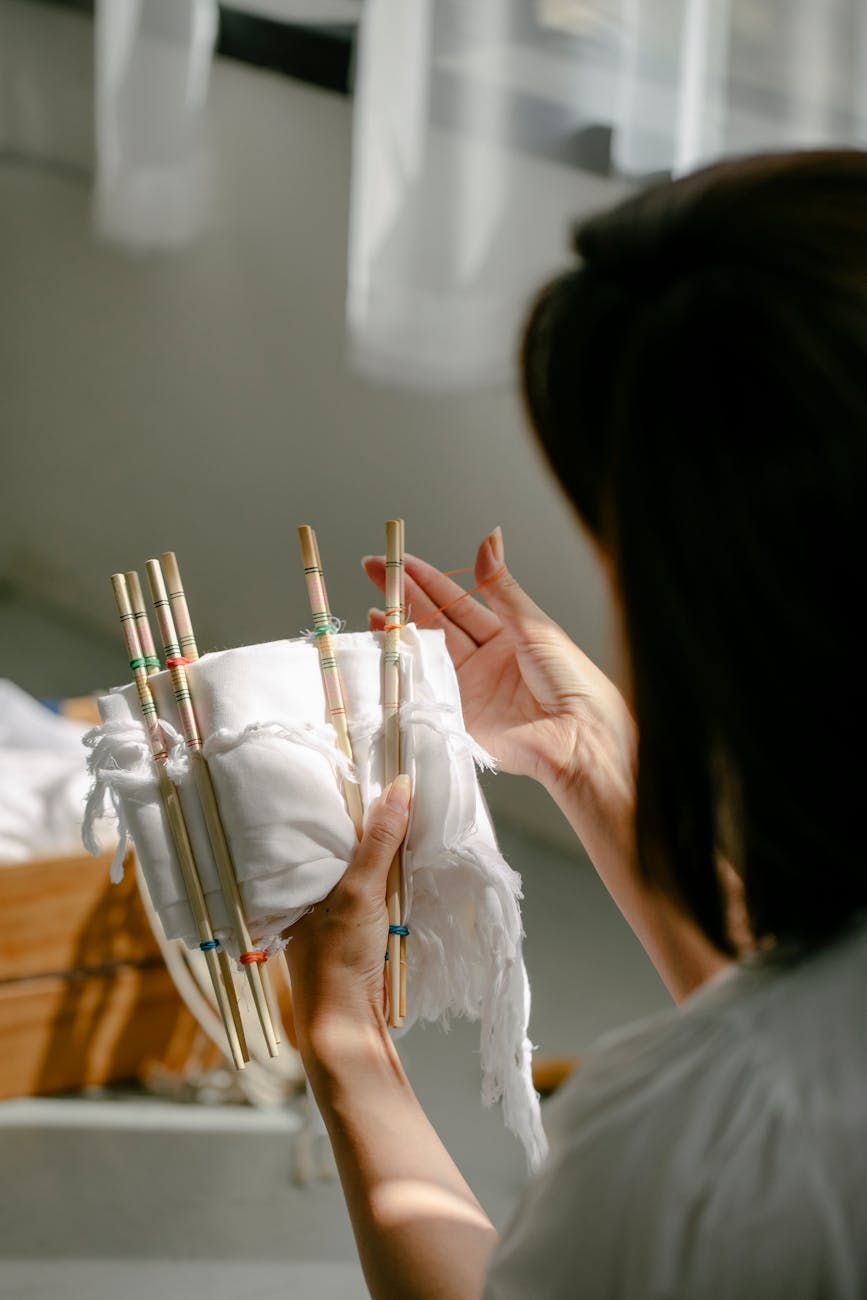 Hands applying gold lacquer to a cracked ceramic bowl on a wooden workspace with kintsugi tools and materials nearby.