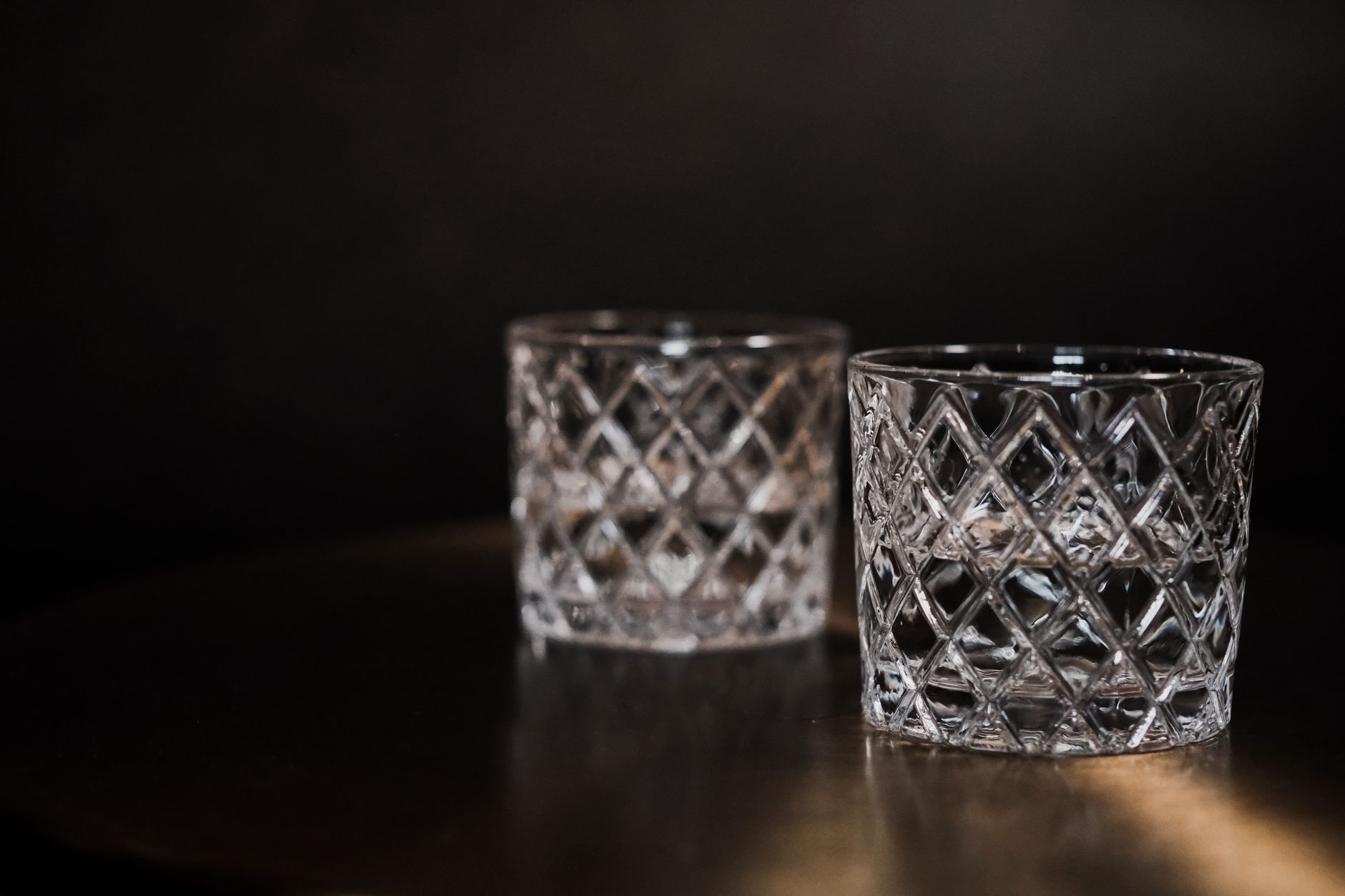 Close-up of Edo Kiriko clear glass with geometric diamond cuts beside Satsuma Kiriko colored glass with deeper floral patterns.