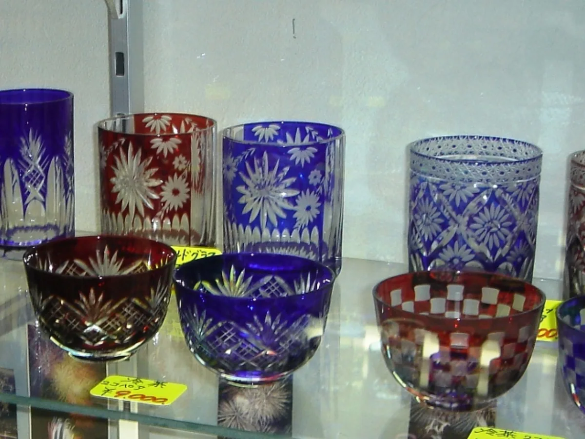 Close-up of Edo Kiriko clear glass with geometric diamond cuts beside Satsuma Kiriko colored glass with deeper floral patterns.