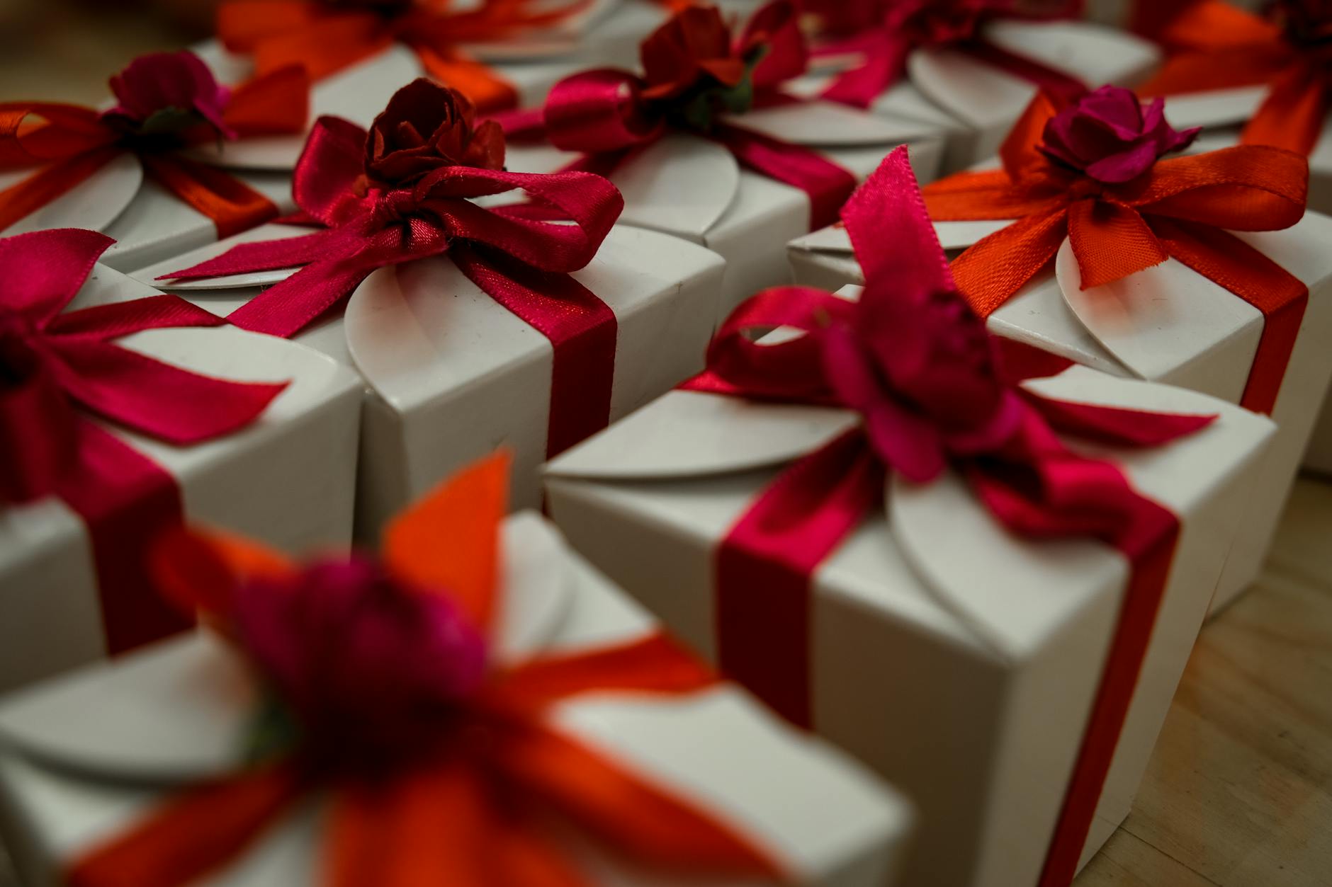 Hands wrapped in kimono sleeves presenting a furoshiki-wrapped gift box with precise folded corners and decorative knot.