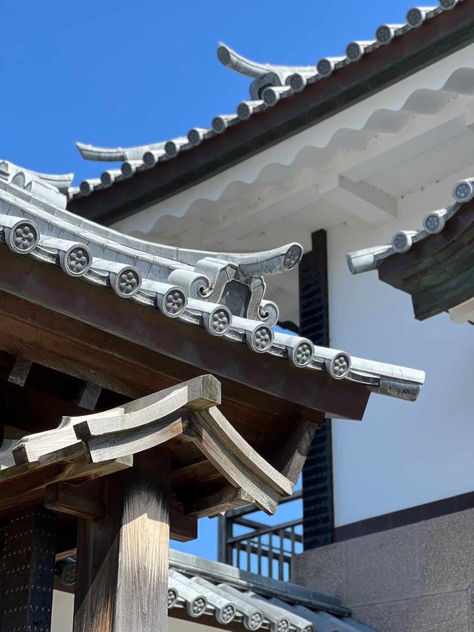 Traditional Japanese engawa veranda with wooden floorboards extending along a house exterior, overlooking a peaceful garden with stone lantern.