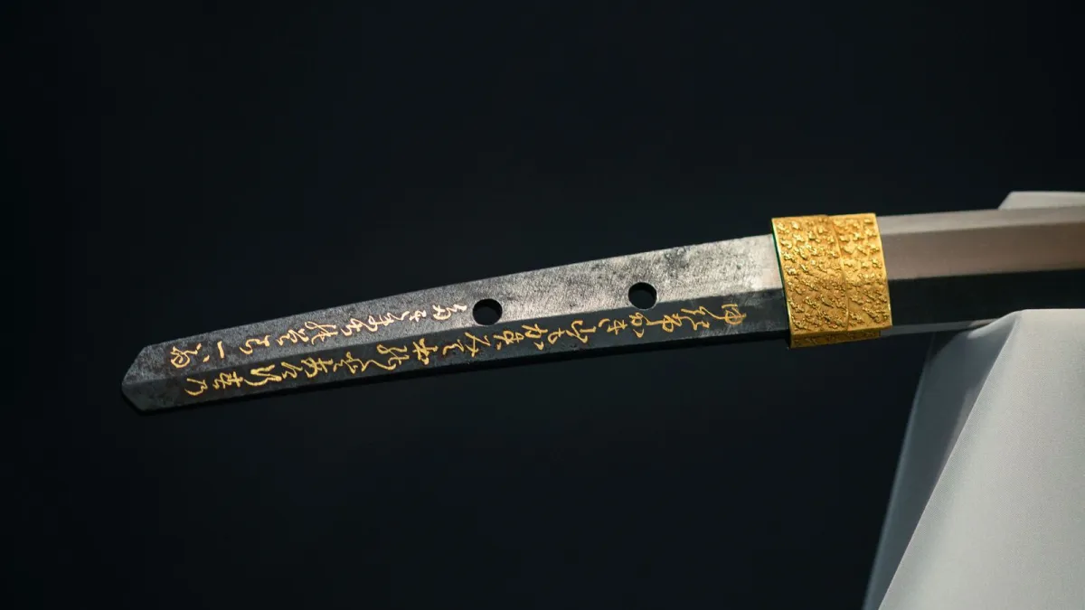 A curved katana blade showing the wavy hamon temper line along its polished edge