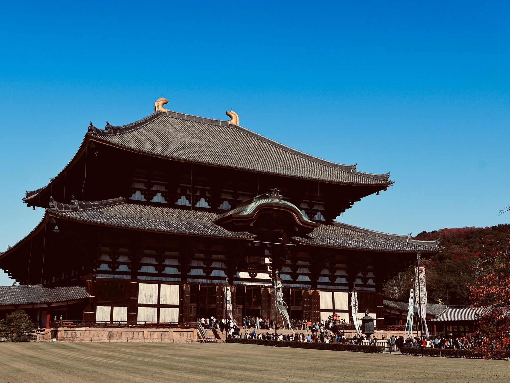 Edo period street scene with wooden merchant shops, tiled roofs, and people in traditional kimono walking along a stone-paved road.