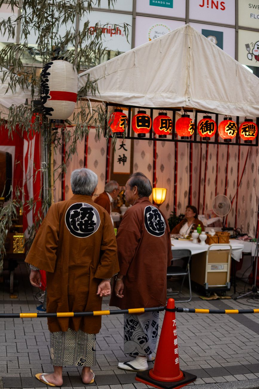 Families gather at a Buddhist altar decorated with lanterns, incense, and offerings of fruit during Obon celebrations in Japan.