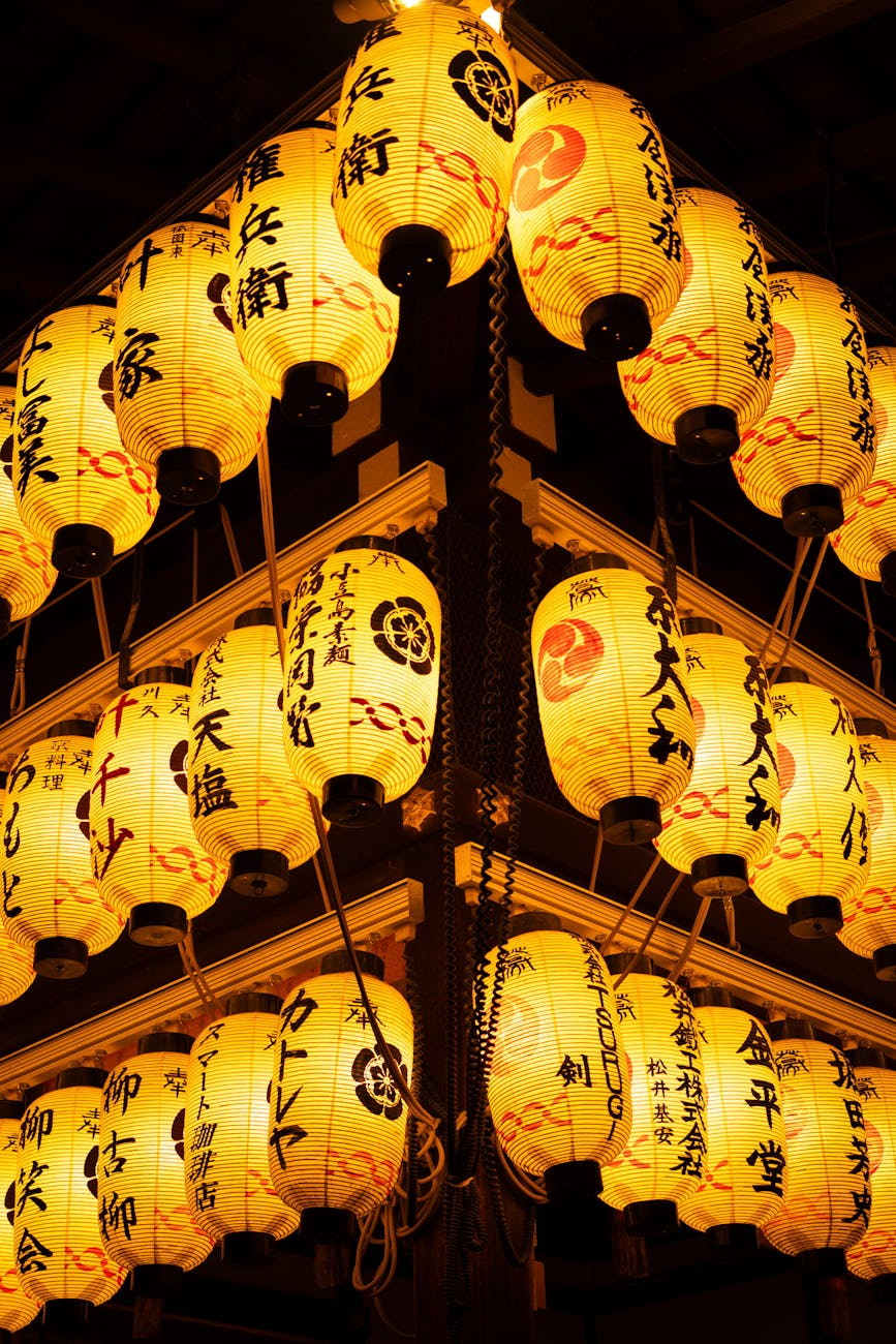 Colorful mikoshi portable shrine carried through crowded street during summer matsuri festival with paper lanterns overhead.