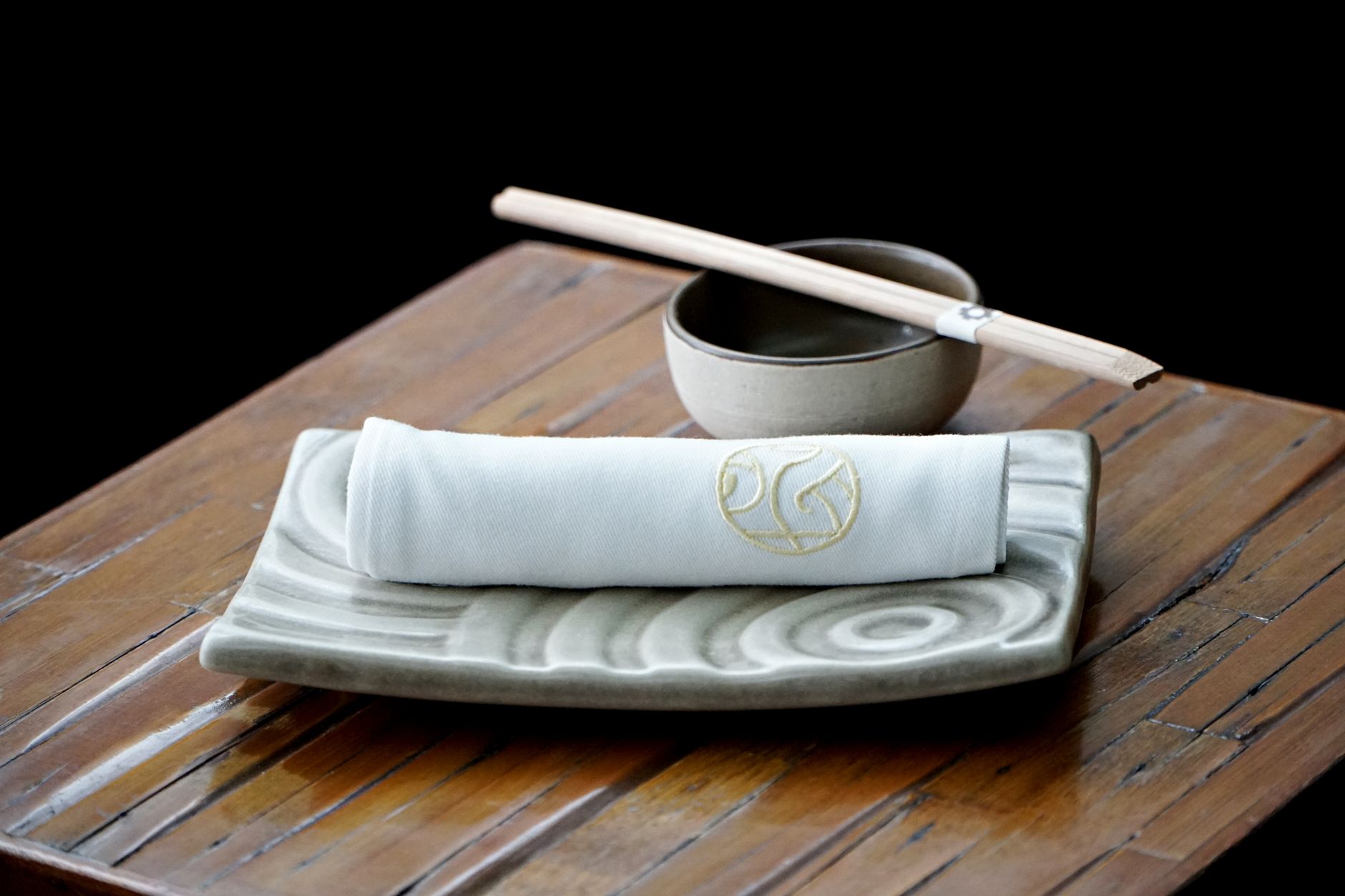 Japanese family gathering around a low table with various dishes, chopsticks resting on holders, and tea cups arranged properly.