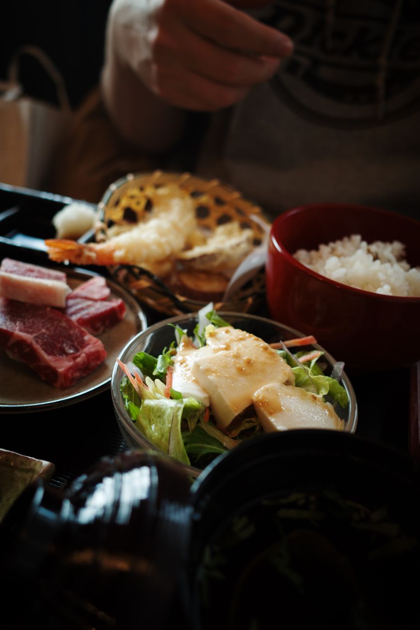 Japanese family gathering around a low table with various dishes, chopsticks resting on holders, and tea cups arranged properly.