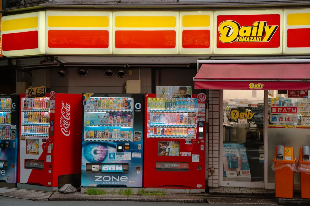 A row of brightly lit drink vending machines glowing on a quiet Japanese street at night