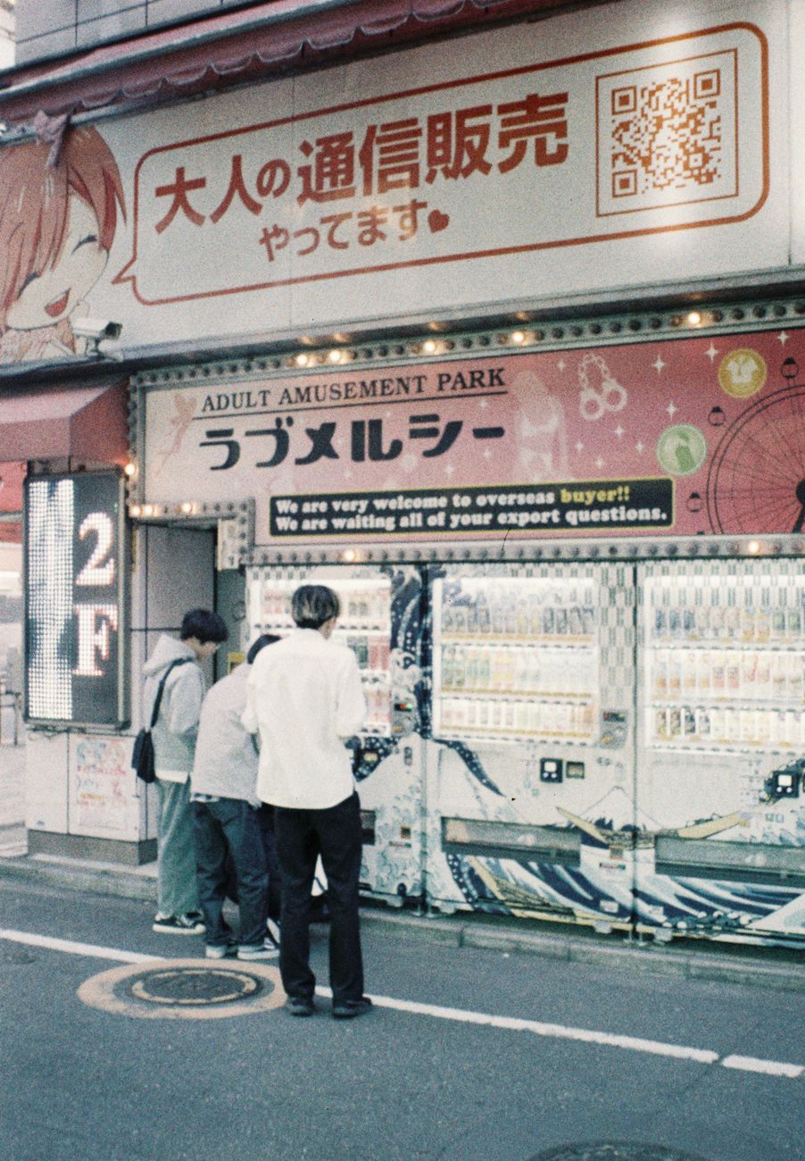 Row of illuminated vending machines on a quiet Tokyo street at night, displaying colorful drinks and snacks through glass fronts.