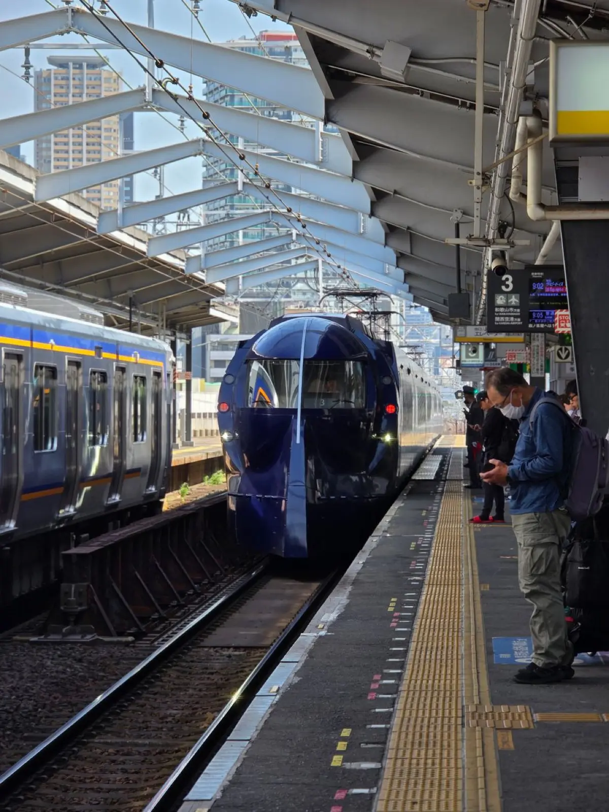 A white and blue Shinkansen bullet train arriving precisely at a Japanese station platform