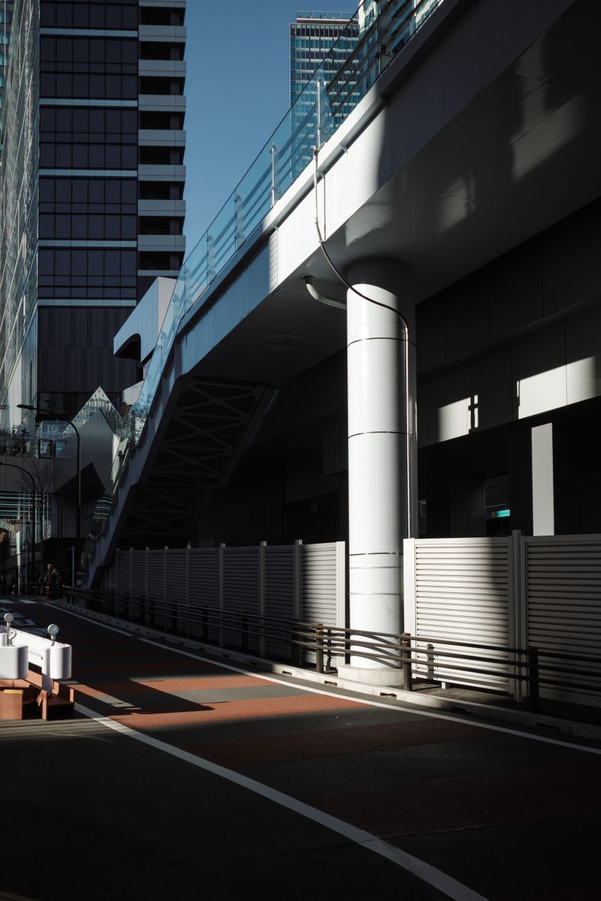 Clean Tokyo residential street with potted plants, bicycles parked neatly, and spotless pavement showing typical Japanese urban neighborhood maintenance.