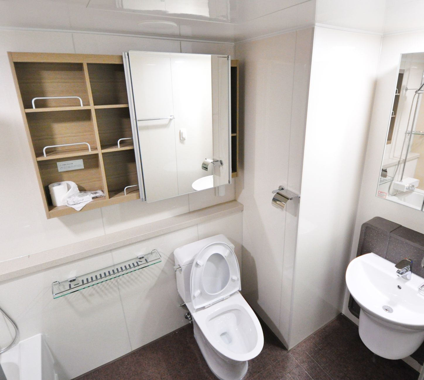Modern Japanese toilet with electronic bidet control panel mounted on bathroom wall showing temperature and pressure buttons