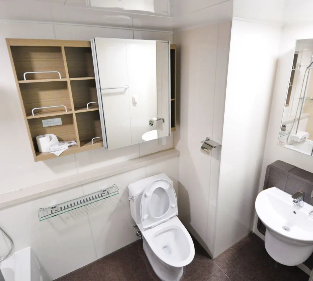 A modern Japanese washlet toilet with an electronic control panel on the wall beside it