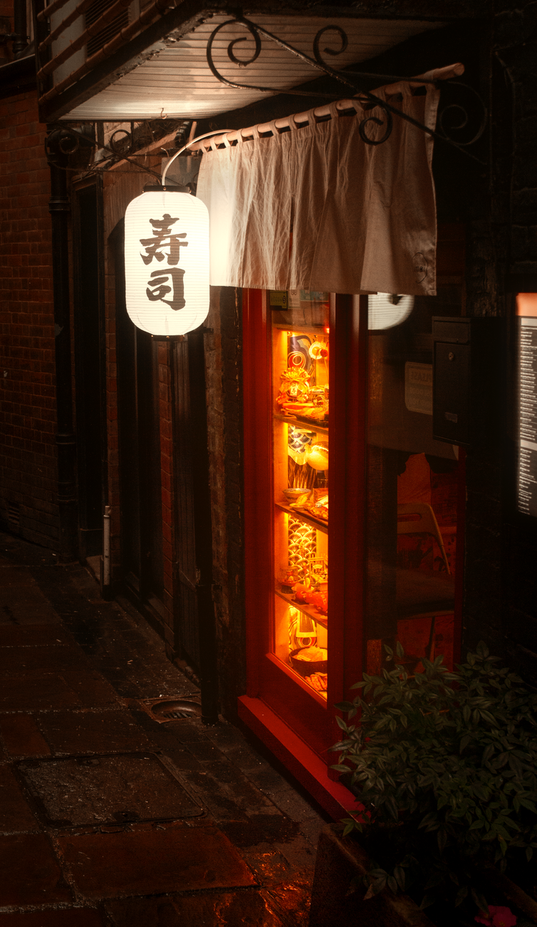 Colorful plastic food samples including ramen, sushi, and tempura arranged in a Japanese restaurant display window in Tokyo.