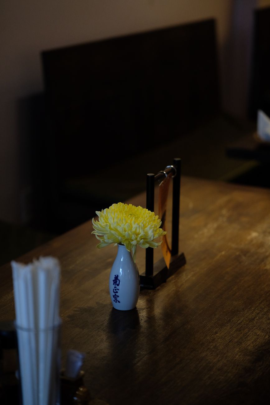 White cotton oshibori hand towel rolled on a ceramic tray beside chopsticks at a traditional Japanese restaurant table setting.