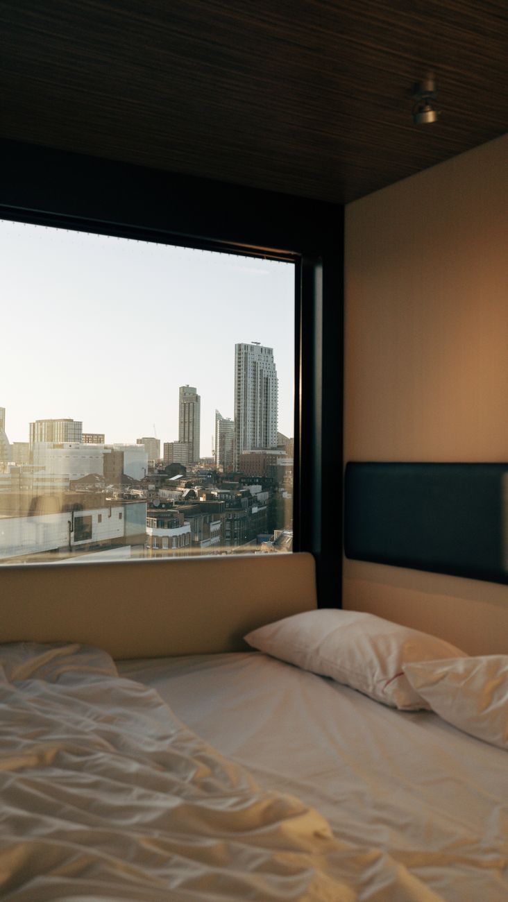A row of stacked sleeping pods with curtains in a minimalist Japanese capsule hotel interior with soft lighting.
