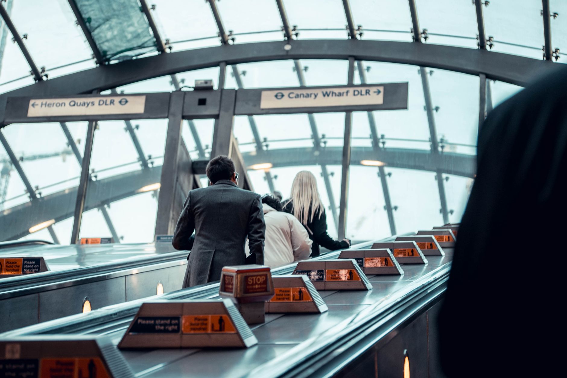 Commuters standing in a single-file line on the left side of a Tokyo metro station escalator during morning rush hour.