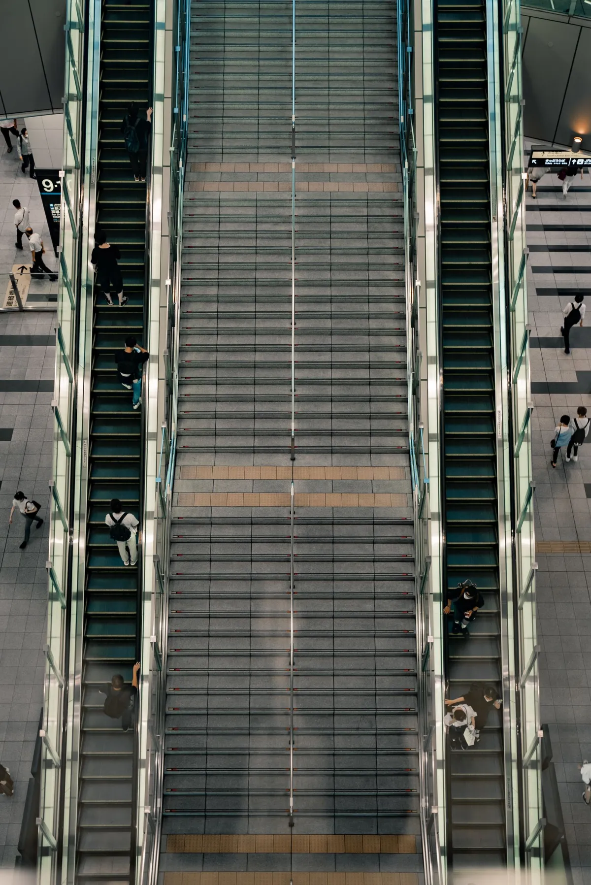 Commuters standing in a single-file line on the left side of a Tokyo metro station escalator during morning rush hour.