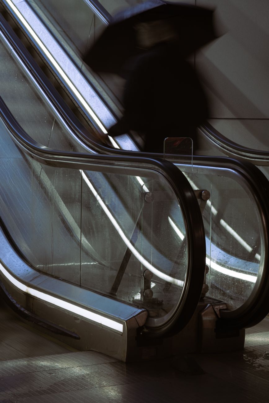 Commuters standing in a single-file line on the left side of a Tokyo metro station escalator during morning rush hour.