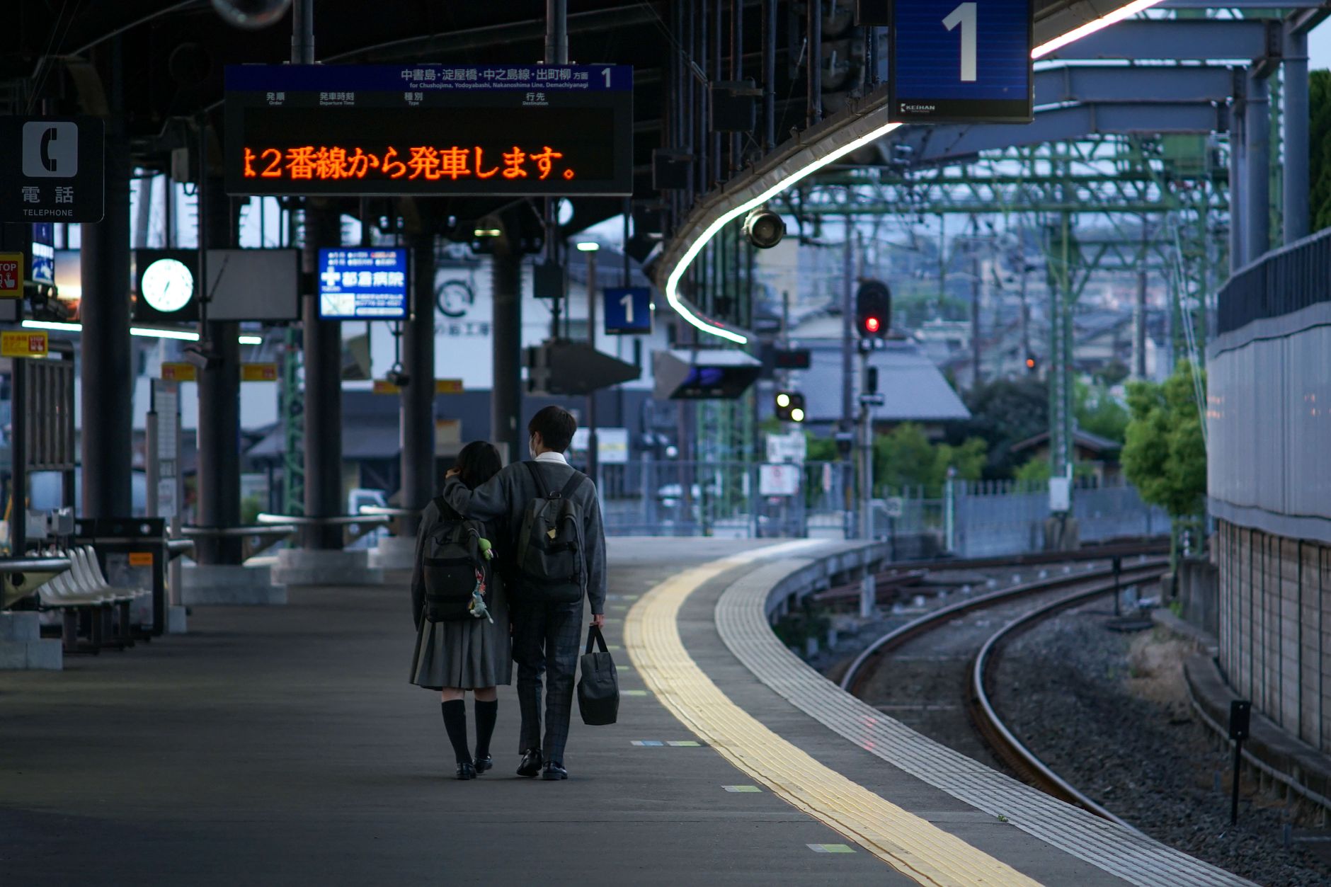 Commuters standing in orderly lines marked on a Tokyo train platform, waiting for the subway doors to align perfectly.