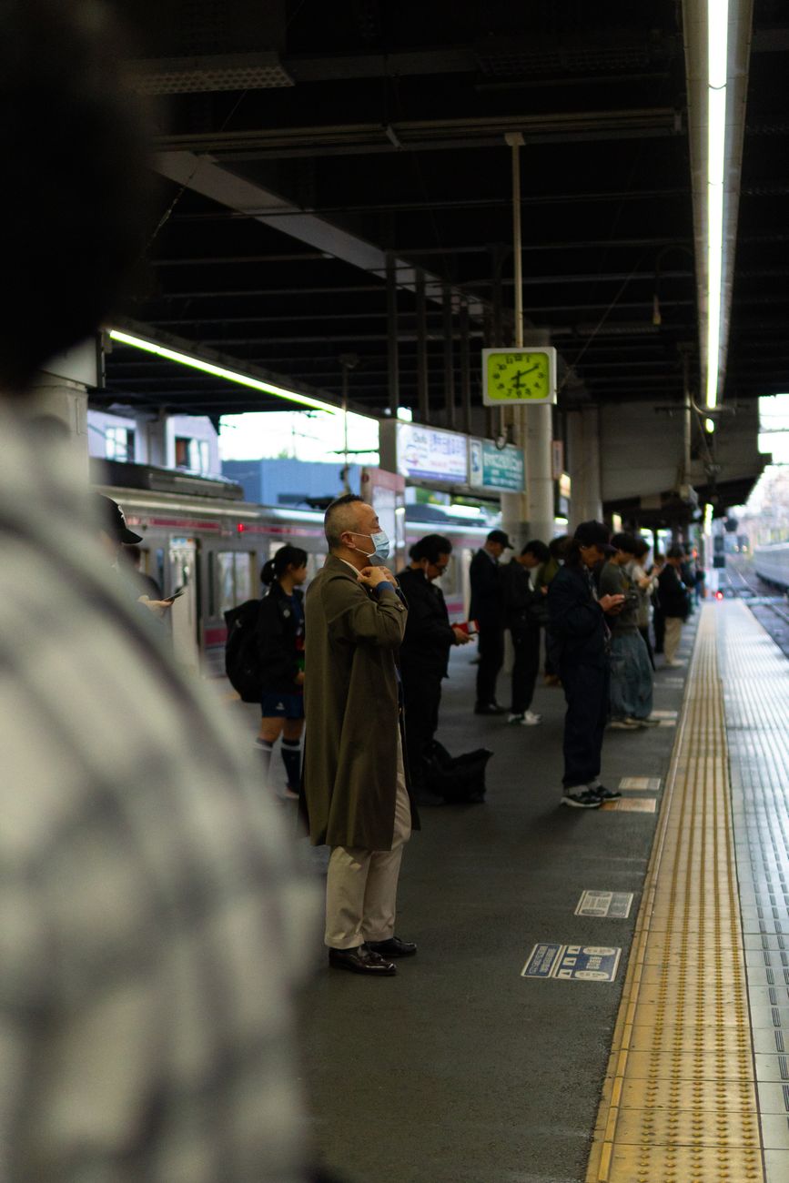 Commuters standing in orderly lines marked on a Tokyo train platform, waiting for the subway doors to align perfectly.