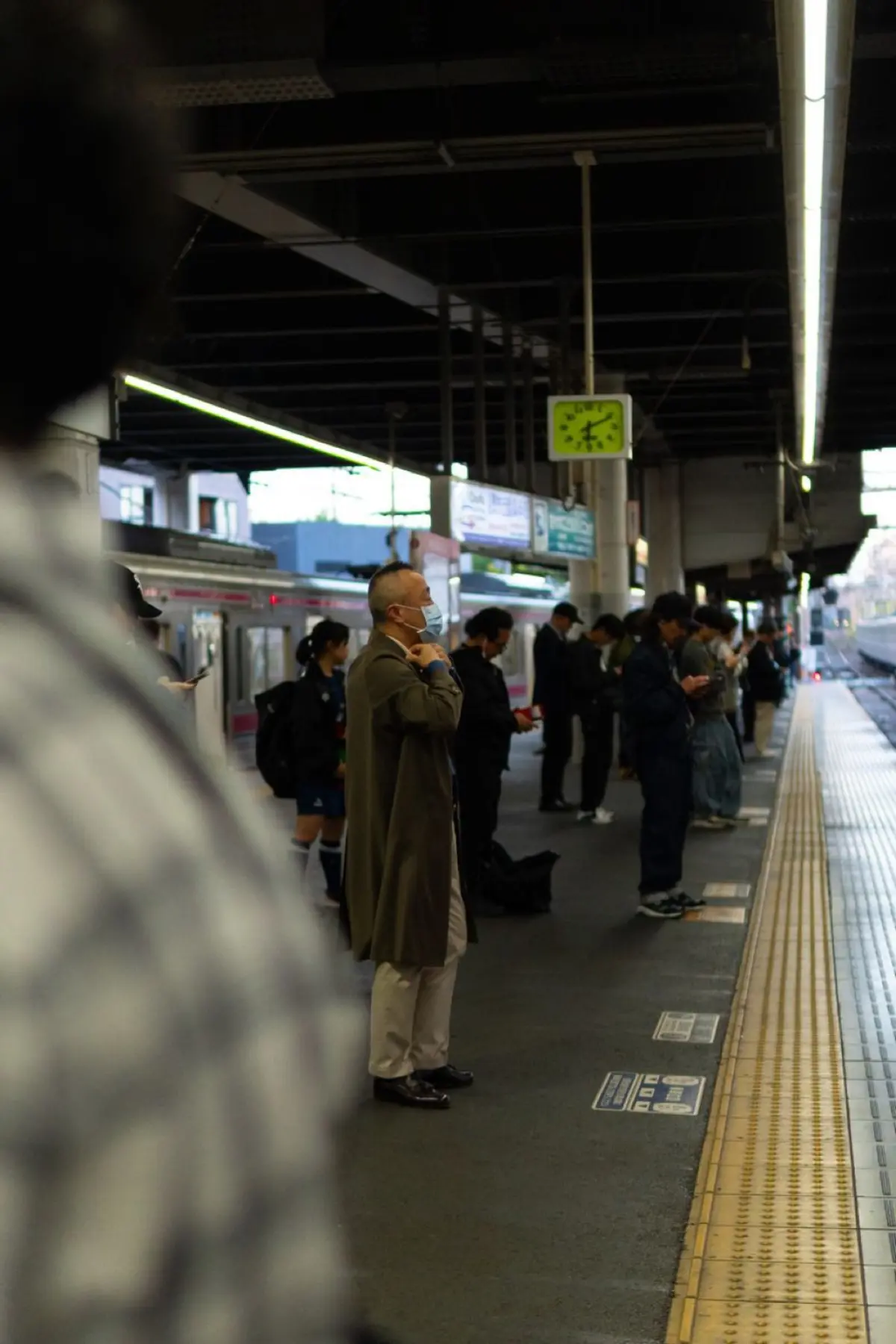 Commuters standing in two neat orderly lines at marked spots on a Japanese train platform