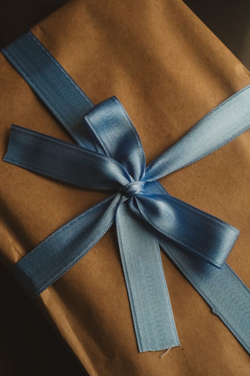 Silk furoshiki cloth wrapping a ceramic teapot using traditional Japanese folding technique with precise corners and elegant knot.