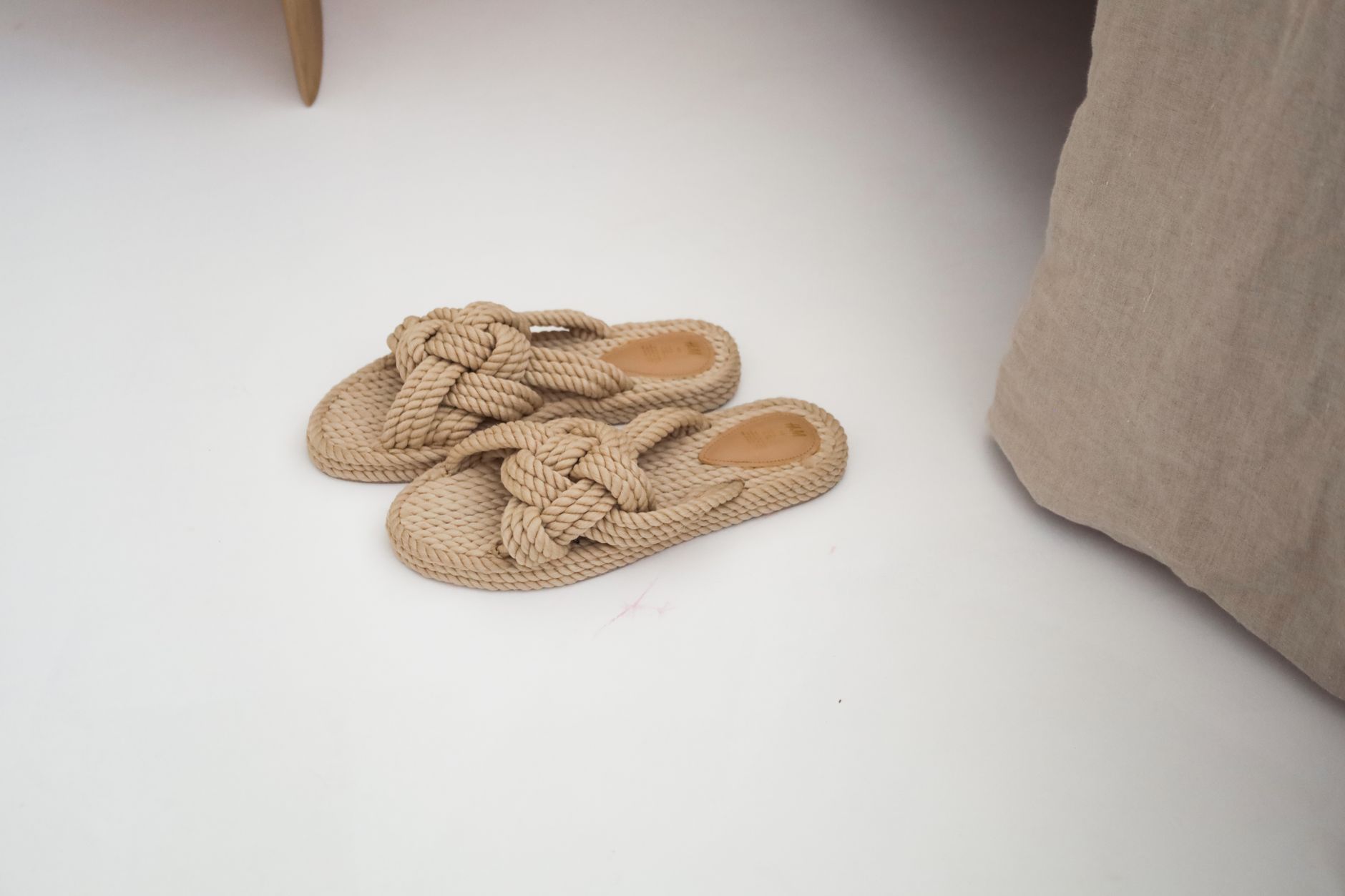Traditional Japanese toilet slippers placed outside a bathroom door in a home with wooden flooring and tatami mats.
