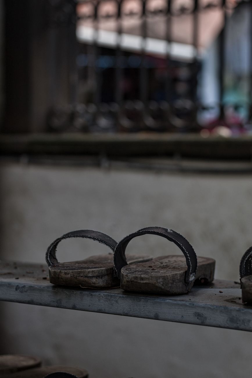 Traditional Japanese toilet slippers placed outside a bathroom door in a home with wooden flooring and tatami mats.