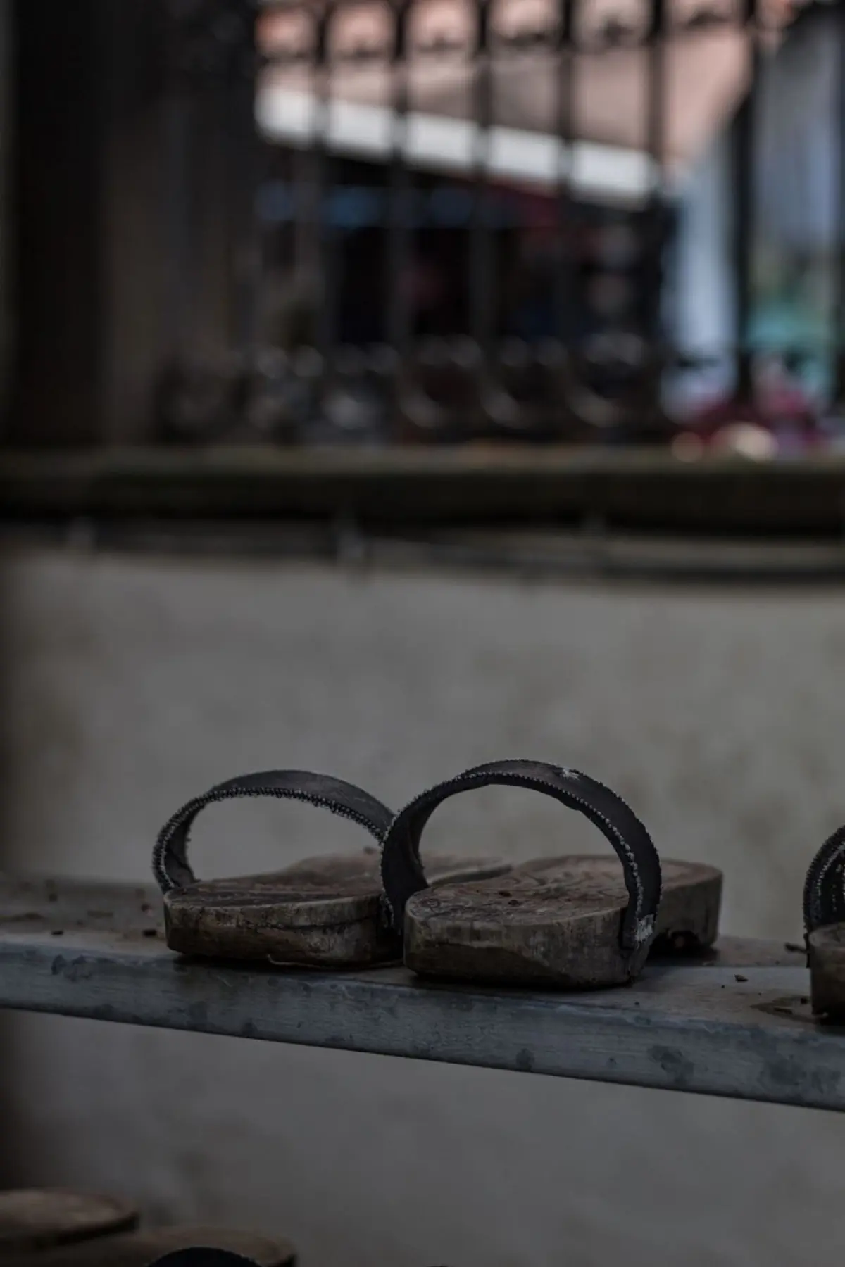 Traditional Japanese toilet slippers placed outside a bathroom door in a home with wooden flooring and tatami mats.