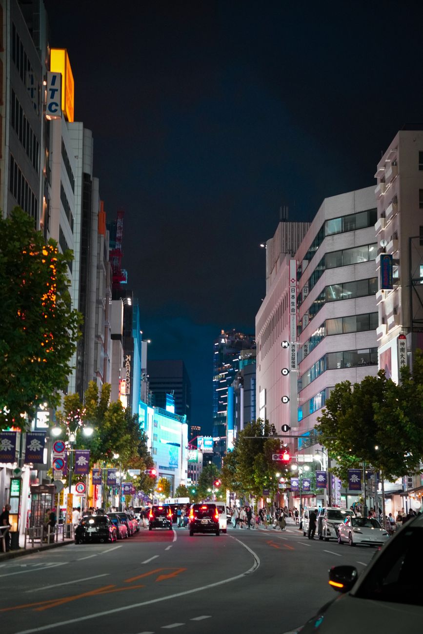 Quiet Tokyo street illuminated by warm vending machine lights and neon signs with no pedestrians visible at midnight.