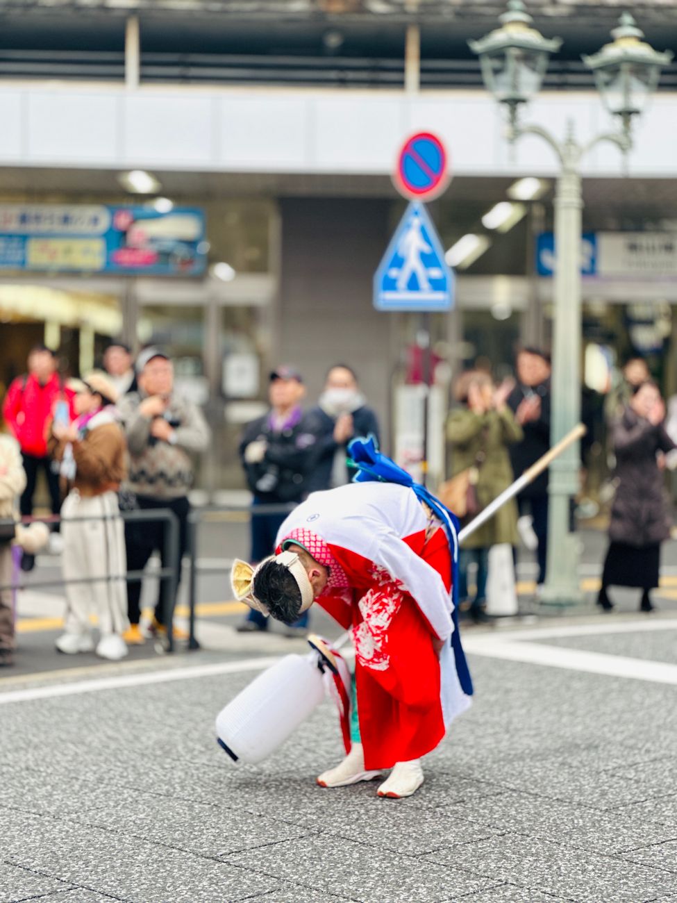 Two Japanese businesspeople bowing to each other at different angles on a city street in formal attire.