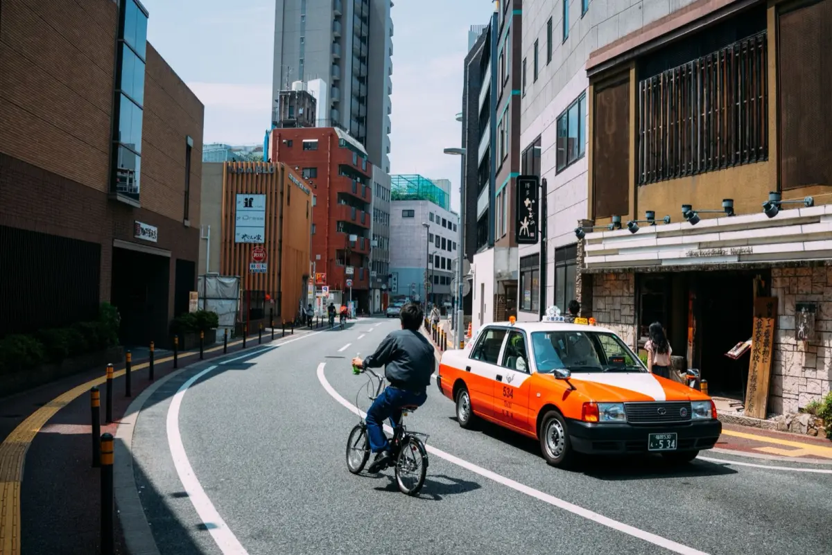 The rear passenger door of a black Japanese taxi opening automatically at the kerb