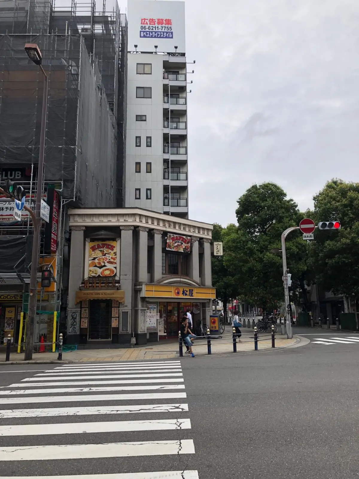 Pedestrians waiting patiently at a red traffic light on an empty Tokyo street intersection during daytime.