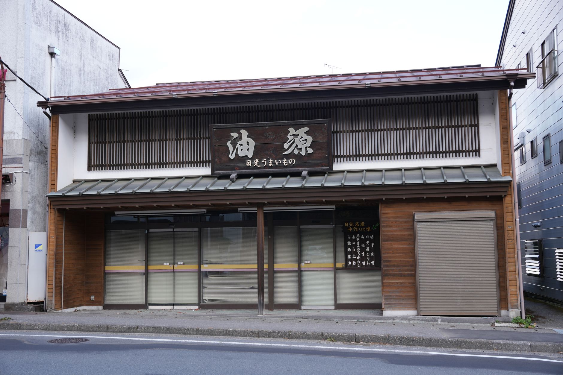 Traditional Japanese onsen entrance with wooden signage displaying bathing rules and tattoo prohibition symbol in natural hot spring setting.