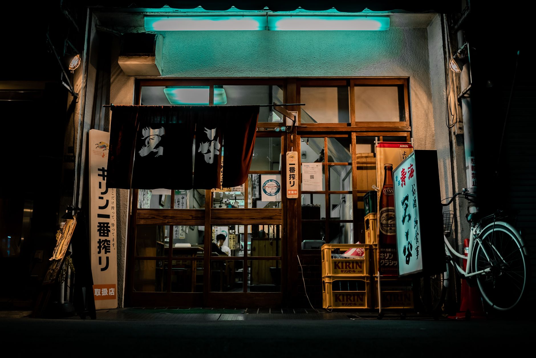 Traditional Japanese restaurant interior showing a wooden table with a small electronic call button device next to chopsticks and tea cups.