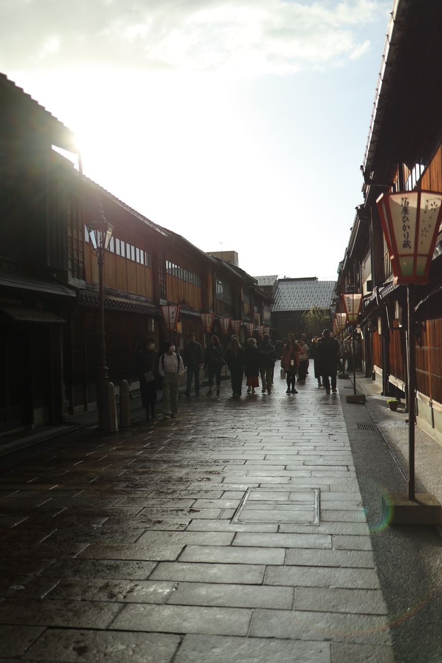 Traditional wooden machiya townhouses line a narrow stone-paved street in Kyoto's historic Higashiyama district at dusk.