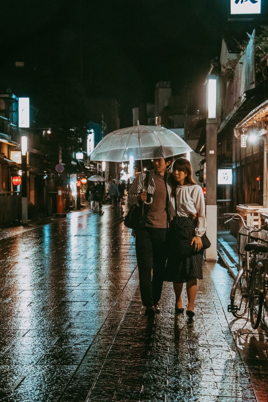 Two Japanese people bowing politely to each other on a city street in a gesture of apology or gratitude.