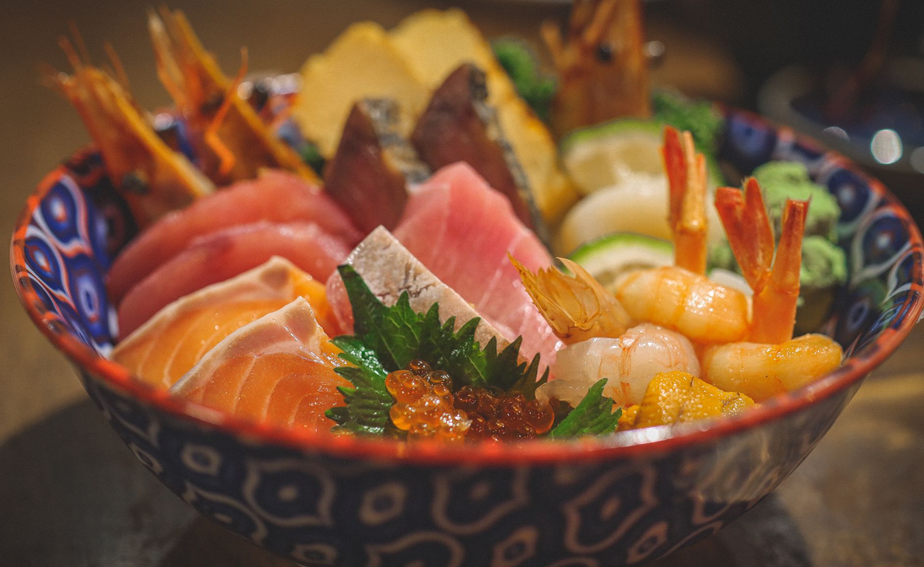 Person holding a traditional Japanese rice bowl in both hands while eating with chopsticks at a dining table.