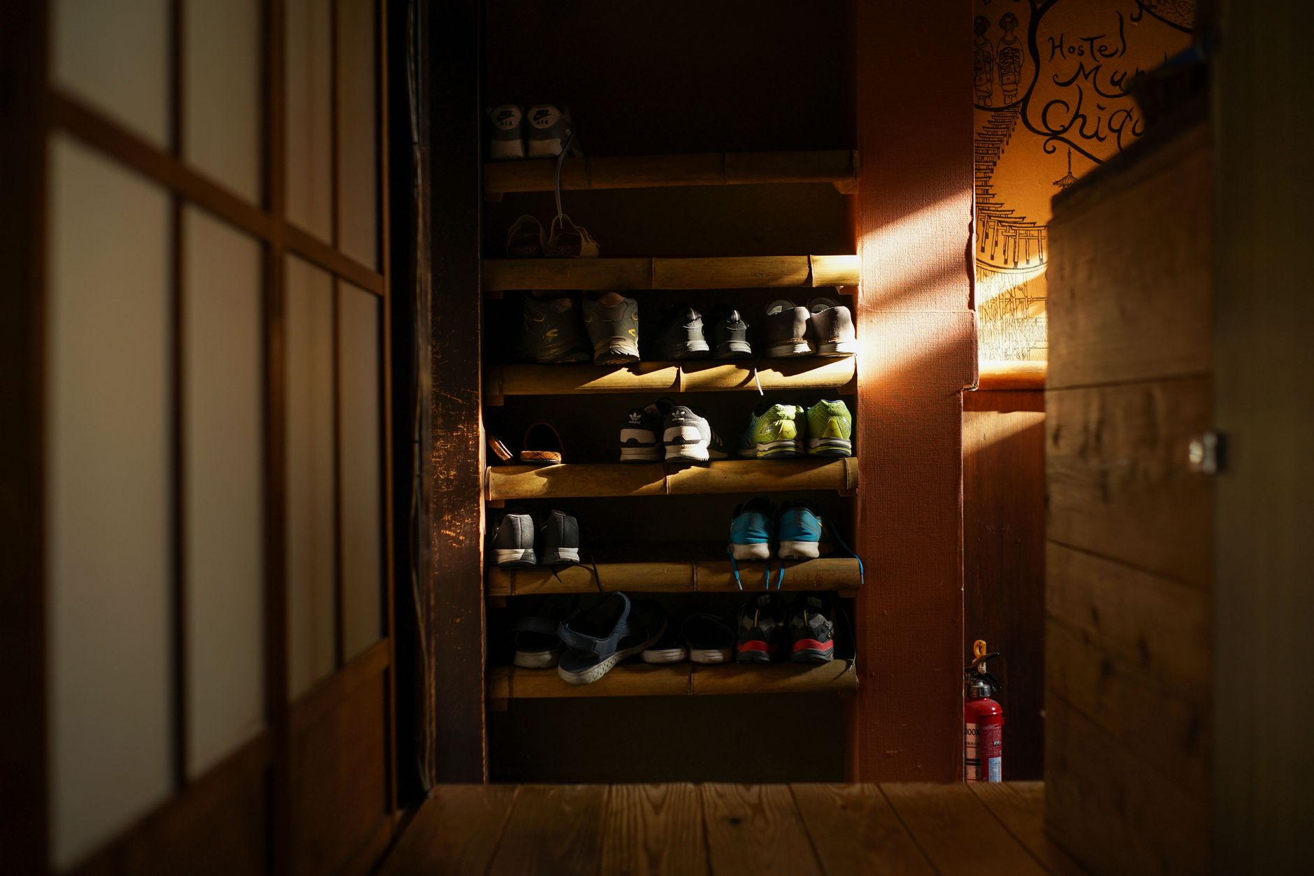 Traditional Japanese genkan entrance showing lowered stone floor area with wooden step leading to raised interior and neatly arranged shoes.