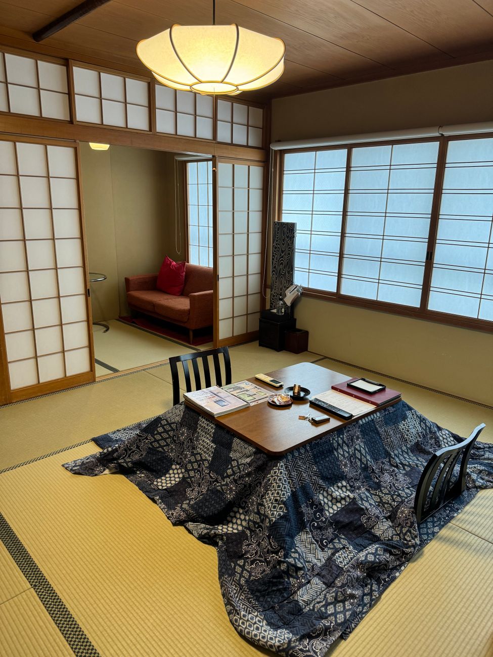 Family gathered around a low wooden kotatsu table covered with a thick quilted blanket in a traditional Japanese living room.