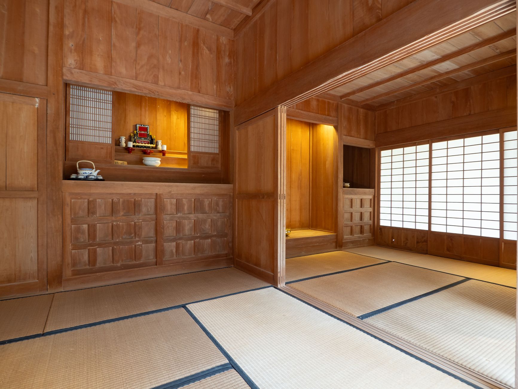 Traditional Japanese futon mattress and pillow neatly folded on tatami mat flooring in a minimalist room with shoji screens.